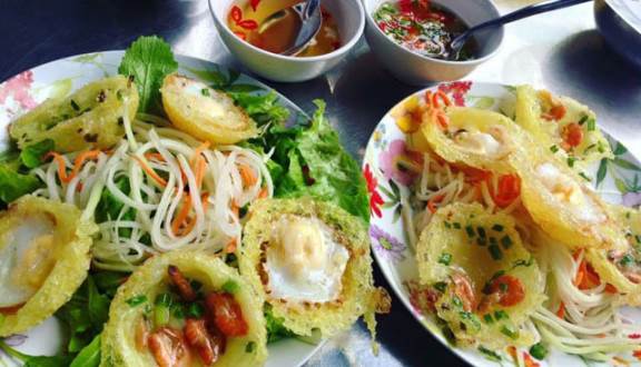Đĩa bánh căn giòn rụm ăn kèm nước mắm chua ngọt, đu đủ bào sợi ngâm chua, rau sống, dưa leo và hai thanh chả đầy đặn có giá 15.000 đồng/đĩa